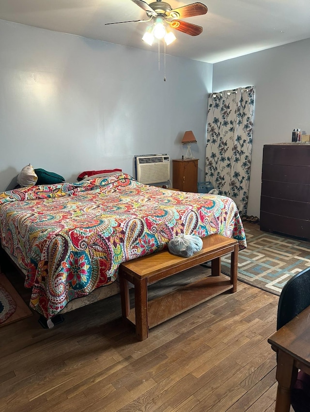 bedroom with hardwood / wood-style flooring, ceiling fan, and a wall mounted AC