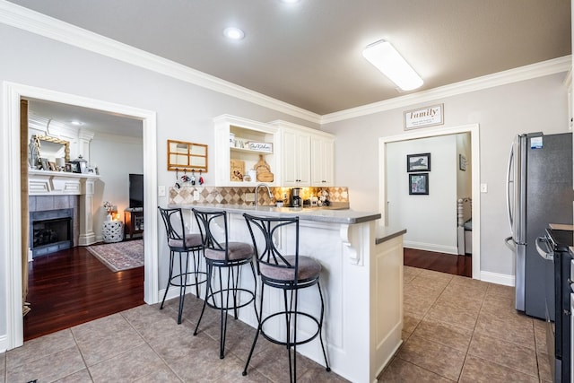 kitchen with white cabinets, a breakfast bar area, tile patterned floors, and stainless steel refrigerator