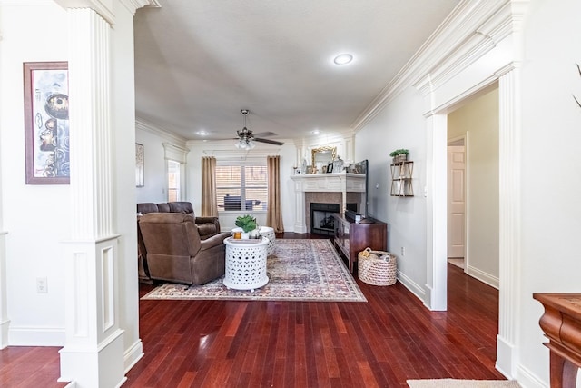 living room with crown molding, ceiling fan, a fireplace, and decorative columns