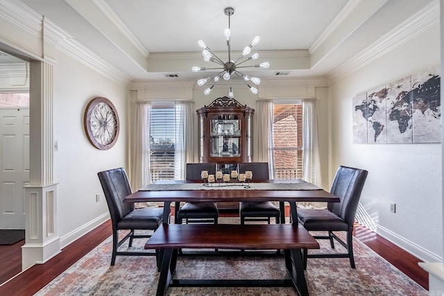 dining room with dark hardwood / wood-style flooring, a notable chandelier, crown molding, and a raised ceiling