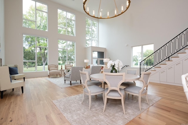 dining room featuring a high ceiling, a notable chandelier, and light hardwood / wood-style floors