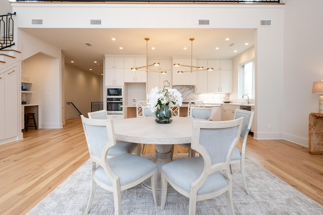 dining room featuring sink, a notable chandelier, and light hardwood / wood-style floors