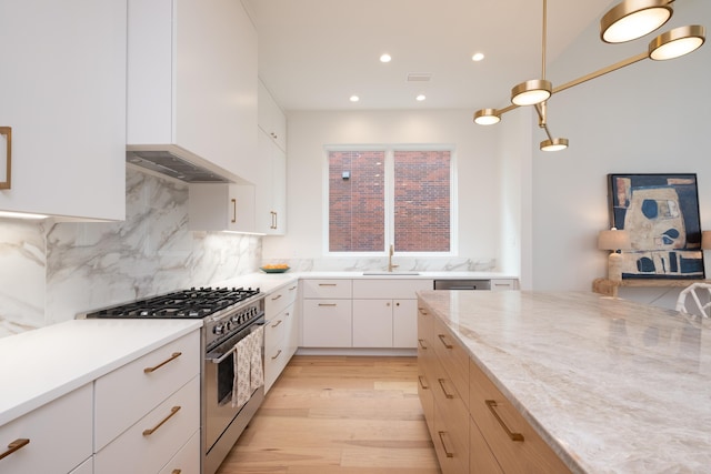 kitchen with high end range, white cabinetry, hanging light fixtures, backsplash, and light stone counters