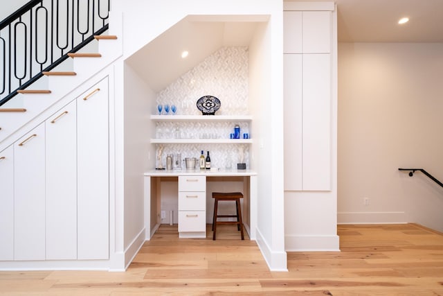 bar with white cabinetry, decorative backsplash, and light hardwood / wood-style floors