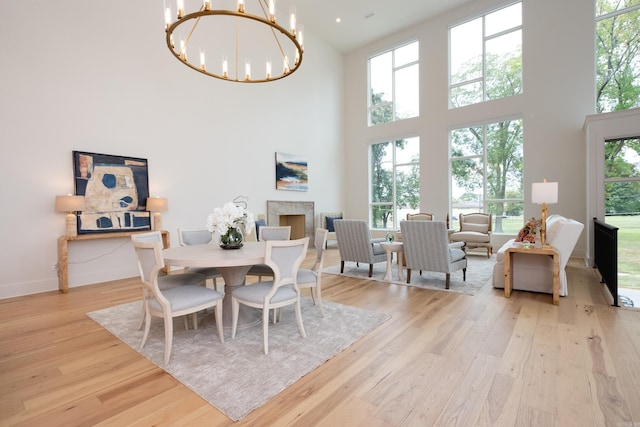 dining space featuring a notable chandelier, light wood-type flooring, and a high ceiling