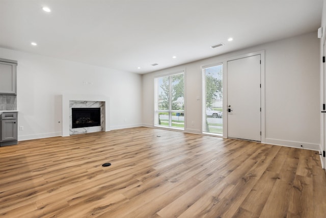 unfurnished living room with a premium fireplace and light wood-type flooring