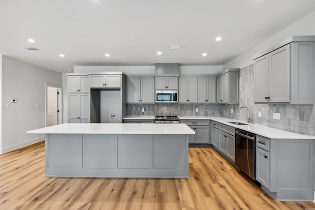 kitchen with a kitchen island, sink, gray cabinetry, stainless steel appliances, and light wood-type flooring