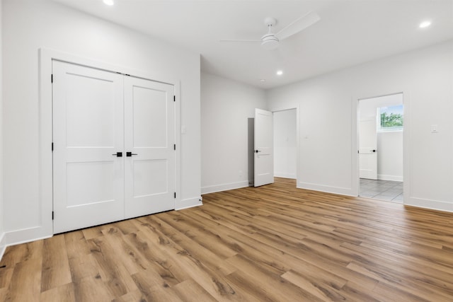 unfurnished bedroom with light wood-type flooring, ceiling fan, and a closet