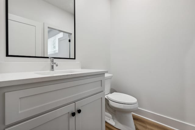 bathroom with vanity, toilet, and hardwood / wood-style floors