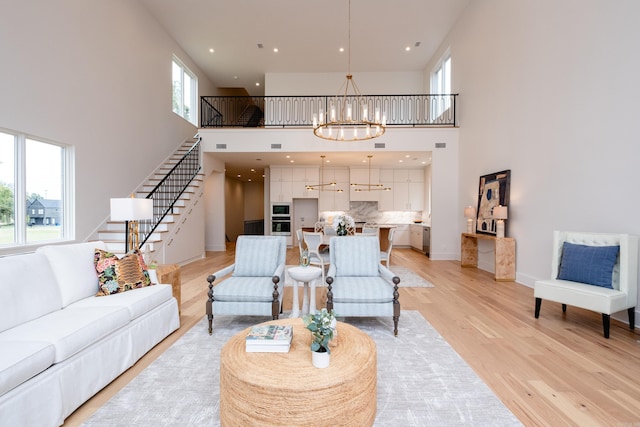 living room with an inviting chandelier, light hardwood / wood-style flooring, and a high ceiling