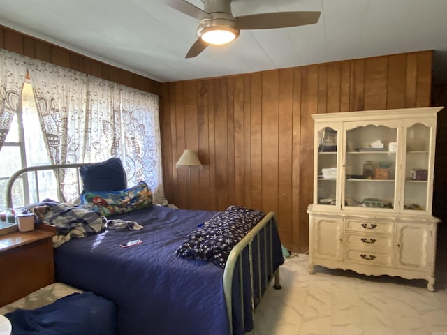 bedroom with ceiling fan and wood walls