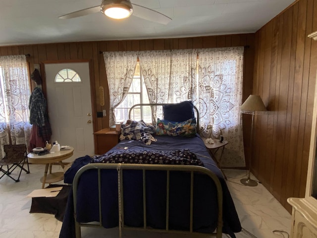 bedroom featuring ceiling fan and wood walls