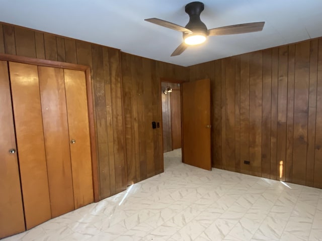 unfurnished bedroom with wooden walls and ceiling fan