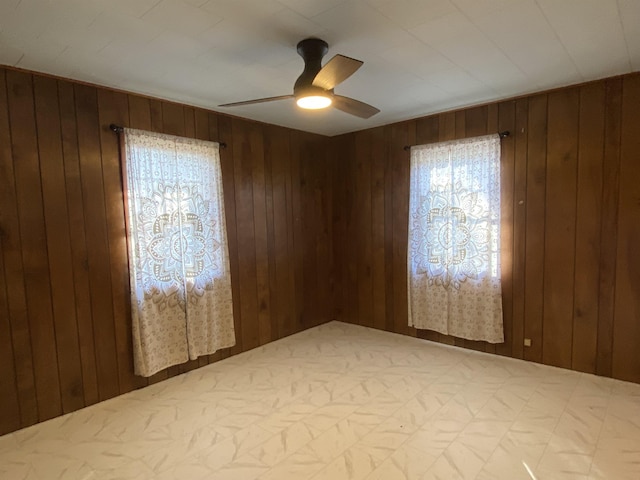 spare room featuring ceiling fan and wood walls