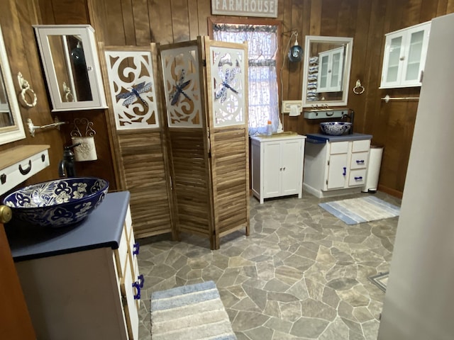 kitchen featuring white cabinetry, sink, and wooden walls