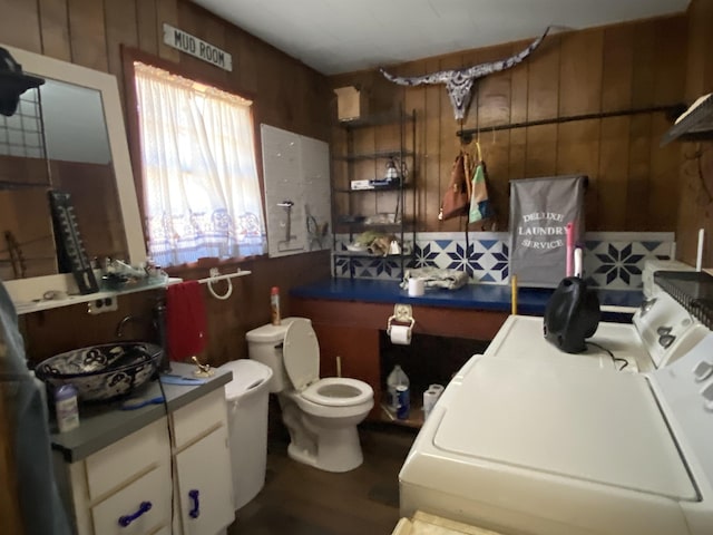 bathroom featuring washer / dryer, wooden walls, and toilet