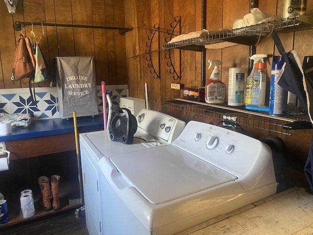 clothes washing area featuring washer and dryer and wood walls