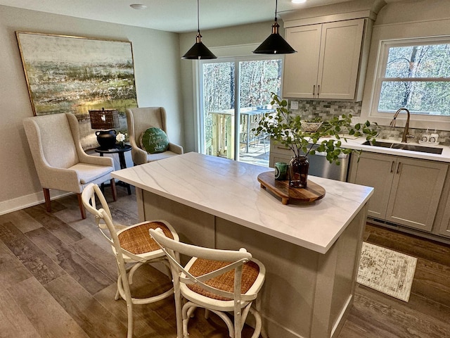 kitchen featuring a kitchen bar, sink, dark hardwood / wood-style flooring, pendant lighting, and decorative backsplash