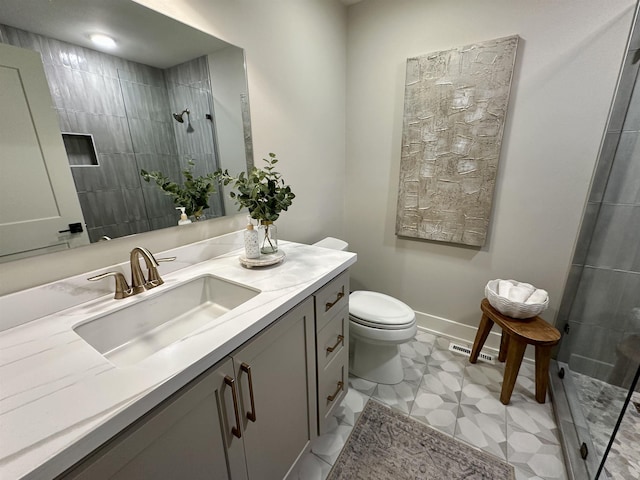 bathroom with vanity, toilet, and tiled shower