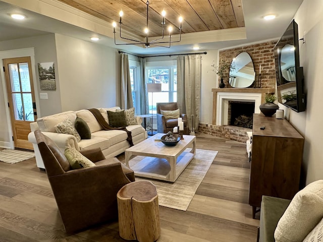 living room with a brick fireplace, wood ceiling, wood-type flooring, and a raised ceiling