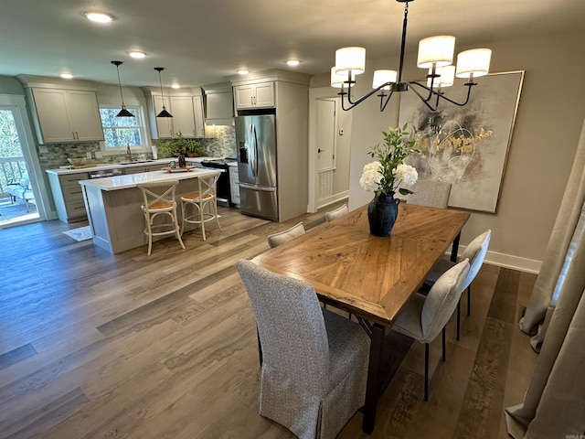 dining area featuring wood-type flooring, a chandelier, and sink