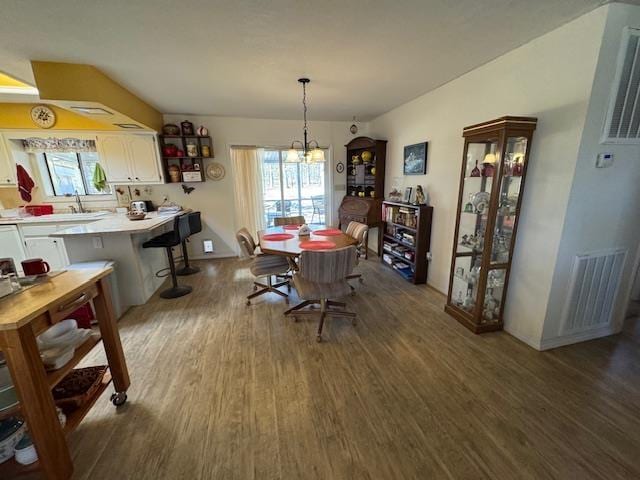 dining space featuring dark hardwood / wood-style flooring, sink, and a notable chandelier