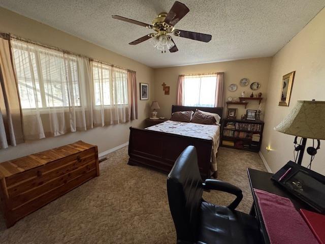 carpeted bedroom featuring ceiling fan and a textured ceiling