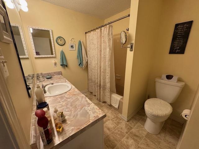 full bathroom featuring vanity, shower / tub combo, toilet, and a textured ceiling