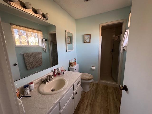 bathroom with wood-type flooring, toilet, an enclosed shower, and vanity