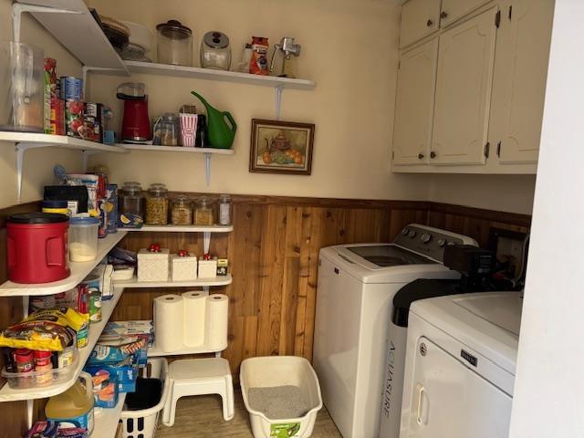 washroom with cabinets, washer and clothes dryer, and wood walls