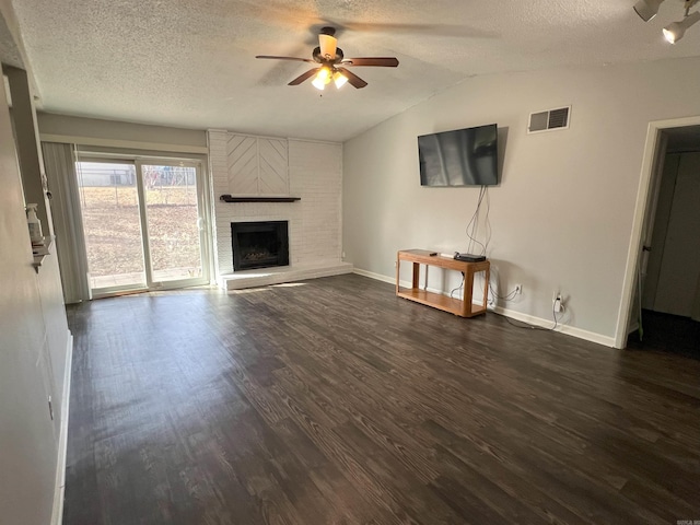 unfurnished living room featuring ceiling fan, a textured ceiling, dark hardwood / wood-style flooring, a brick fireplace, and vaulted ceiling