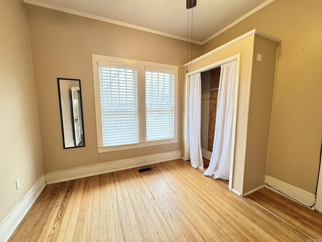 unfurnished bedroom with light hardwood / wood-style flooring, ornamental molding, and a closet