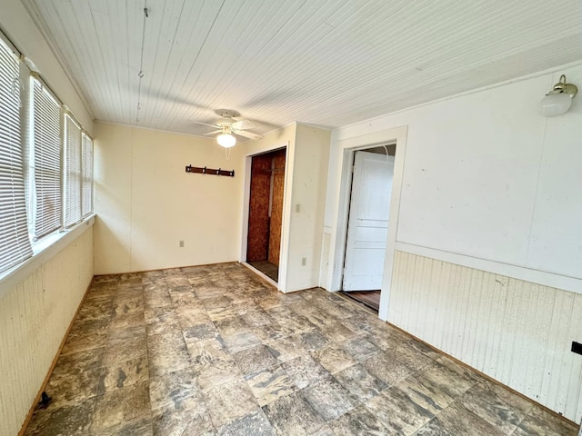 spare room featuring ceiling fan and wood walls