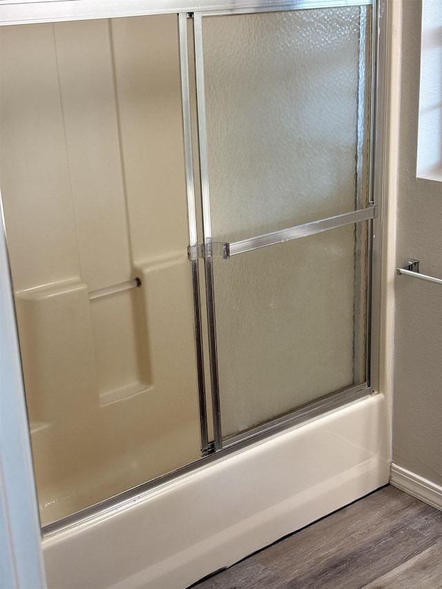 bathroom featuring bath / shower combo with glass door and wood-type flooring