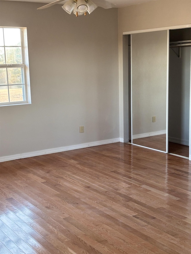 unfurnished bedroom with ceiling fan, wood-type flooring, and a closet