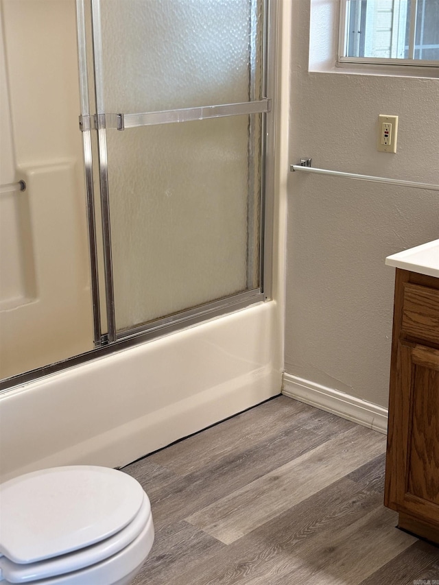 full bathroom featuring vanity, wood-type flooring, toilet, and combined bath / shower with glass door