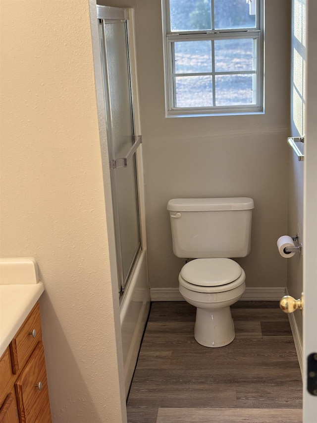 full bathroom featuring vanity, hardwood / wood-style flooring, enclosed tub / shower combo, and toilet