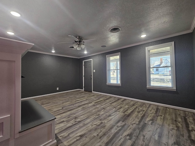 empty room with wood-type flooring, ornamental molding, ceiling fan, and a textured ceiling