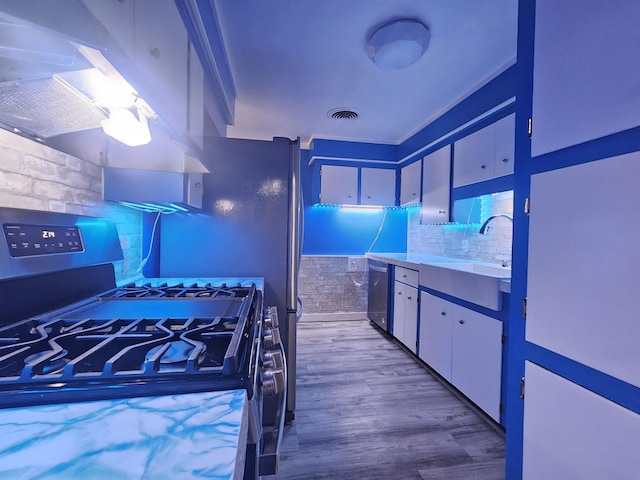 kitchen with sink, white cabinetry, stainless steel appliances, island range hood, and wood-type flooring