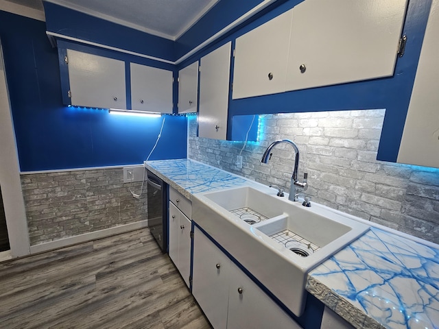 kitchen with light hardwood / wood-style flooring, white cabinetry, backsplash, ornamental molding, and stainless steel dishwasher