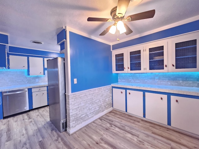 kitchen with stainless steel appliances, tasteful backsplash, light wood-type flooring, brick wall, and white cabinets