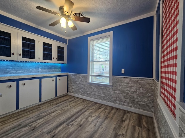 kitchen featuring ceiling fan, brick wall, dark hardwood / wood-style flooring, and white cabinets