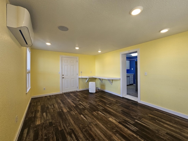 spare room with dark hardwood / wood-style floors, a textured ceiling, and an AC wall unit