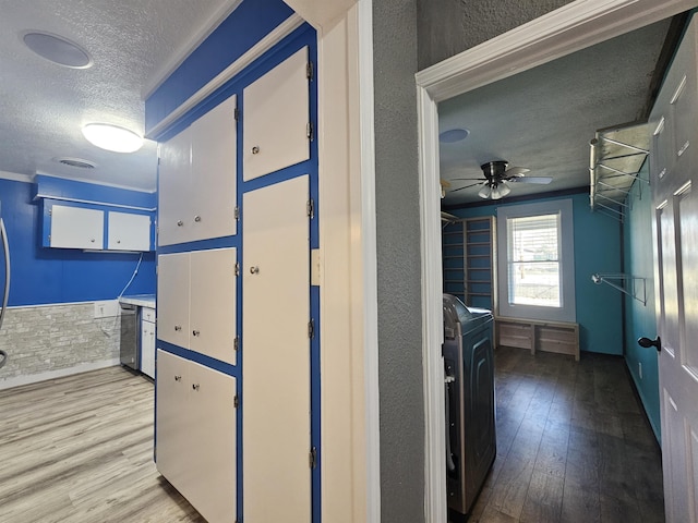 hallway with washer / clothes dryer, a textured ceiling, and light wood-type flooring