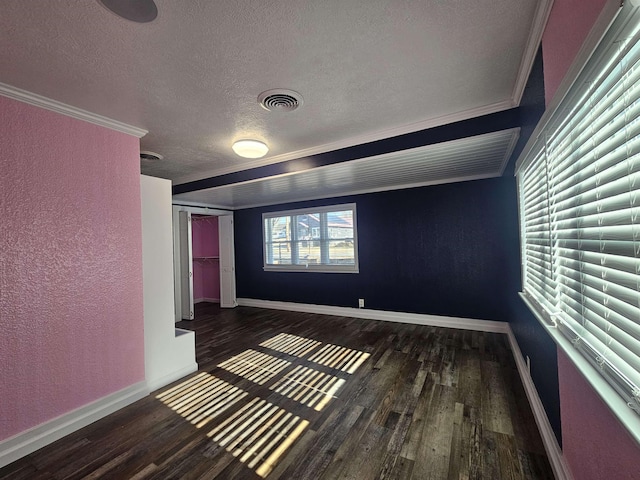 empty room featuring crown molding, dark hardwood / wood-style floors, and a textured ceiling