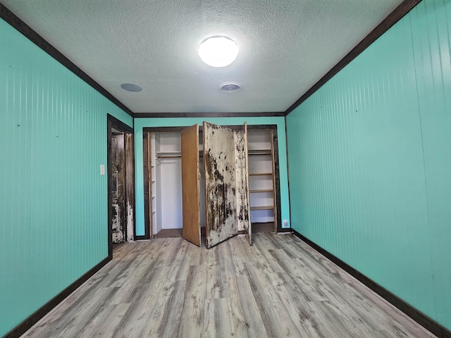 unfurnished bedroom with ornamental molding, light hardwood / wood-style floors, and a textured ceiling