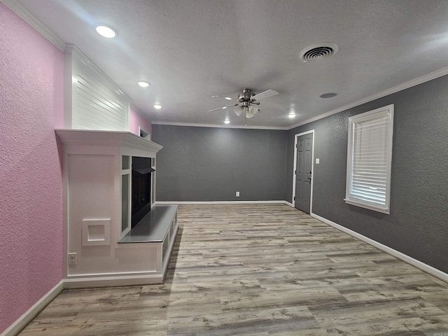 unfurnished living room featuring ceiling fan, ornamental molding, light hardwood / wood-style flooring, and a textured ceiling