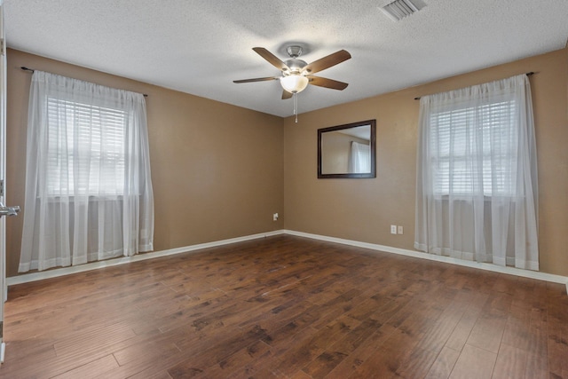 empty room with ceiling fan, dark hardwood / wood-style flooring, and a textured ceiling