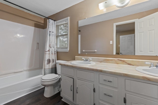 full bathroom featuring shower / bath combo, vanity, wood-type flooring, a textured ceiling, and toilet