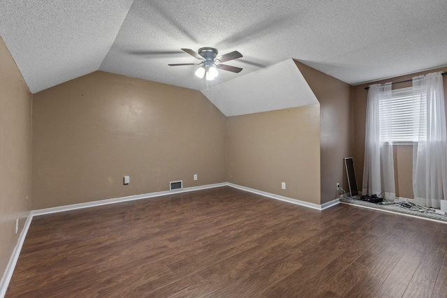 additional living space featuring lofted ceiling, a textured ceiling, dark wood-type flooring, and ceiling fan